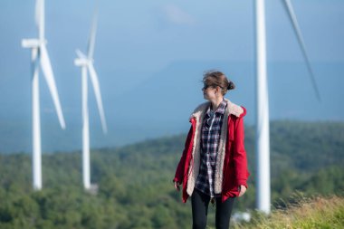 Yel değirmenlerinin arka planında, kırmızı ceketli genç bir kadın kış tatilinin tadını çıkarıyor..