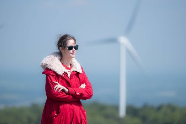 Yel değirmenlerinin arka planında, kırmızı ceketli genç bir kadın kış tatilinin tadını çıkarıyor..