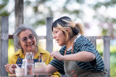 Çömlekçilik atölyesinde, Asyalı emekli bir çift çömlekçilik ve kil boyama faaliyetleriyle meşgul..