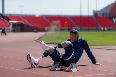 Stadyumda koşmadan önce esneyen ve ısınan engelli bir sporcu.