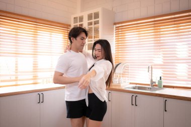 Genç Asyalı çift evdeki mutfakta dans ederken iyi eğlenceler. Mutlu aile kavramı.