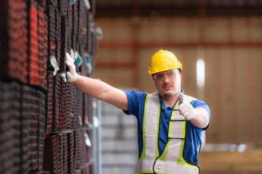 Portrait of a construction worker standing with thumbs up in front of steels material wall clipart