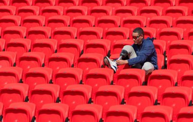 Stadyumdaki kırmızı koltuklarda oturan mavi gömlekli engelli sporcular antrenmana hazır olun..