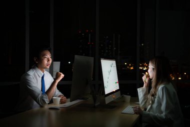 Her iki Asyalı genç borsacı uluslararası borsa simsarları gece ofisindeki masaüstünde birlikte çalışıyorlar. Uluslararası finans şirketi konsepti.