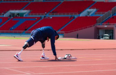 Stadyumda koşmadan önce esneyen ve ısınan engelli bir sporcu.