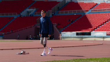 Engelli sporcular, kısa mesafe koşusuna katılmadan önce güneşli bir günde spor sahasında vücutlarını amfitiyatroda hazırlıyorlar.