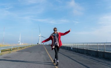 Yel değirmenlerinin arka planında, kırmızı ceketli genç bir kadın kış tatilinin tadını çıkarıyor..
