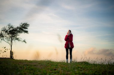 Mavi gökyüzünün arka planında kırmızı ceketli güzel bir genç kadının portresi.