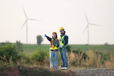 Mühendis ve işçi planlı bir rüzgar türbini çiftliğinde tartışıyorlar.