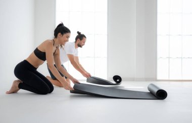 Evde yoga yapan çiftler yoga minderini sarıyorlar.