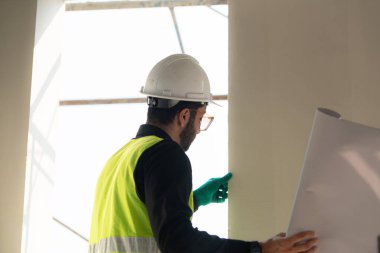 İnşaat alanında çalışan mühendis veya mimar, iki kez kontrol planları ve işlemler.