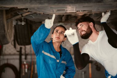 Bir oto tamircisinde çalışan araba tamircisi, oto tamirhanesinde tamirat için gelen arabanın motorunun çalışmasını kontrol ediyor..