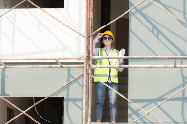 İnşaat alanında çalışan mühendis veya mimar, iki kez kontrol planları ve işlemler.