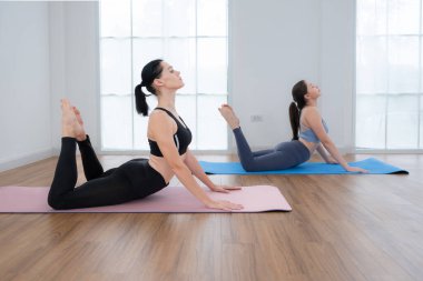 Evde eğitmenle yoga yapan genç bir kadın. Bireysel yoga sınıfı evde pratik yapıyor.