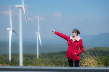 Yel değirmenlerinin arka planında, kırmızı ceketli genç bir kadın kış tatilinin tadını çıkarıyor..