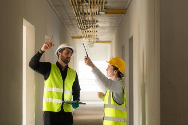 İnşaat alanında çalışan erkek ve kadın mühendisler binanın elektrik sistemini izliyorlar..