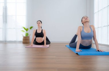 Evde eğitmenle yoga yapan genç bir kadın. Bireysel yoga sınıfı evde pratik yapıyor.