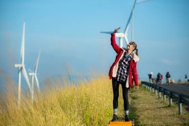 Yel değirmenlerinin arka planında, kırmızı ceketli genç bir kadın kış tatilinin tadını çıkarıyor..