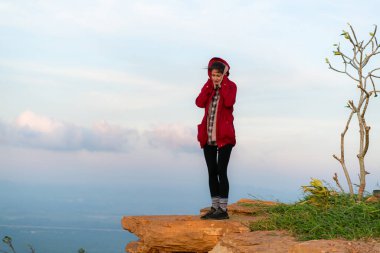 Mavi gökyüzünün arka planında kırmızı ceketli güzel bir genç kadının portresi.