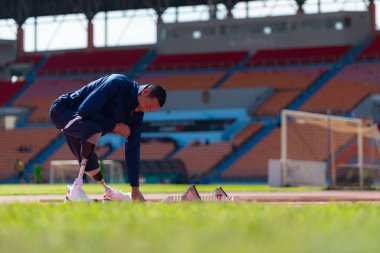 Stadyumda koşmadan önce esneyen ve ısınan engelli bir sporcu.