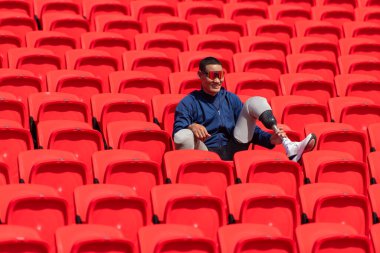 Stadyumdaki kırmızı koltuklarda oturan mavi gömlekli engelli sporcular antrenmana hazır olun..