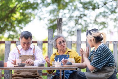 Çömlekçilik atölyesinde, Asyalı emekli bir çift çömlekçilik ve kil boyama faaliyetleriyle meşgul..