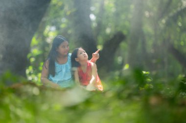 Geleneksel giyim standı olan iki Asyalı kız yağmur ormanlarında birlikte oynayarak eğlendiler..
