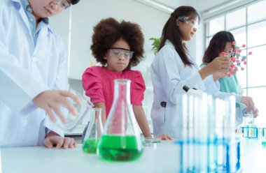 Fen sınıfında, Asyalı bir çocuk bilim adamı kimyasal formüller üzerinde deney yapıyor.