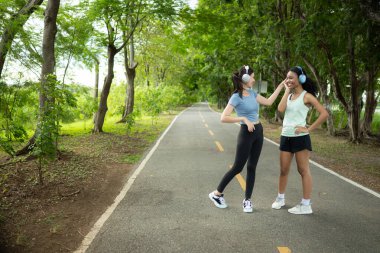 Parkta koşan ve gülümseyen iki genç kadının portresi.