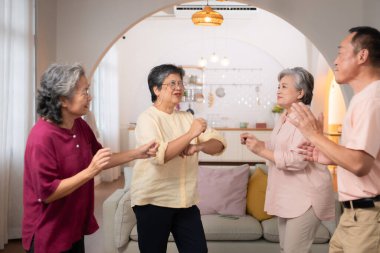 Bir grup yaşlı Asyalı huzur evinde mutlu bir şekilde dans ediyor.
