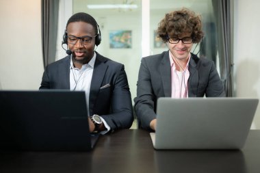 Ofiste çalışan kulaklık takan bir grup iş adamı. Arama merkezi, tele pazarlama, müşteri destek acentesi telefon görüşmesinde hizmet sunar.