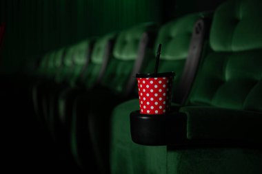 Yeşil koltuklu ve kırmızı bardaklı sinema salonu.