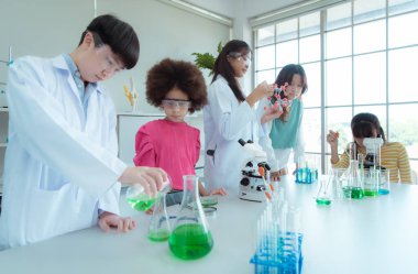 Fen sınıfında, Asyalı bir çocuk bilim adamı kimyasal formüller üzerinde deney yapıyor.