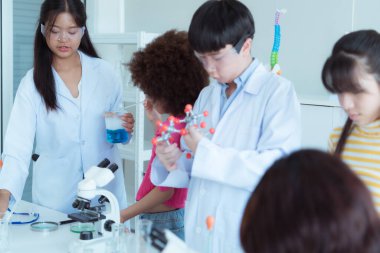 Fen sınıfında, Asyalı bir çocuk bilim adamı kimyasal formüller üzerinde deney yapıyor.