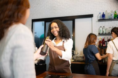 Genç bayan barista, kahve dükkanında kendi fincanlarını getiren müşterilere servis yapıyor..