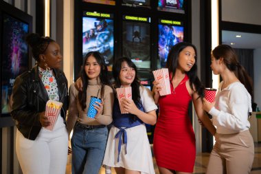 Group of happy friends watching movie in cinema and eating popcorn at night clipart