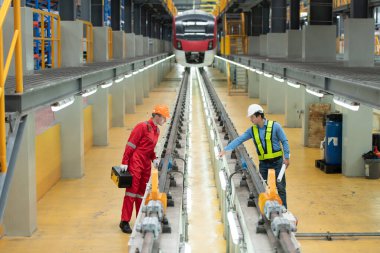 Elektrikli tren tamir atölyesine park edildikten sonra, elektrikli tren mühendisi ve teknisyeni, denetim turuna uygun olarak demiryolu ve elektrik trenlerini teftiş ediyor.