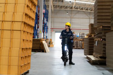 Depoda elektrikli scooterla gezen genç bayan bir depo çalışanı. Burası büyük bir paket depolama ve dağıtım deposu..