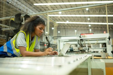 Makineyi kontrol etmek için dizüstü bilgisayar kullanan genç kadın mühendisler..