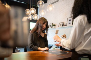 Müşteriler kahve malzemelerini seçer. Kahve dükkanında çalışan genç bir bayan baristayla.
