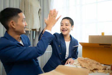 İki Asyalı moda tasarımcısı da gelinlik mağazasında dikiş makinesiyle çalışıyorlar.