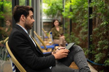 İki işadamı da açık kafede dijital tablet kullanıyor. İş adamları kahve dükkanında buluşuyor..