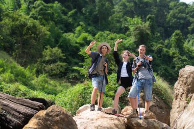 Sırt çantalı bir grup turist nehirde ve dağlarda yürüyor.