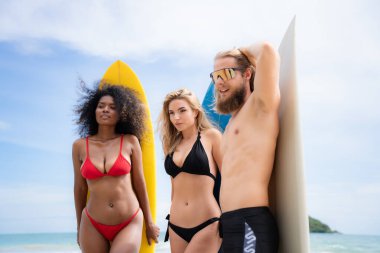 Mayolu bir grup arkadaş sahilde sörf tahtası ile poz veriyorlar..