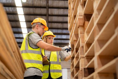 İki işçi de ahşap fabrikasında çalışıyor, ahşap depodaki odunları kontrol ediyorlar.