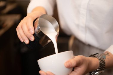 Barista kahve dükkanındaki fincana kahve dolduruyor, yakın plan.