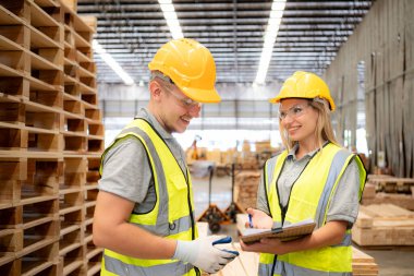 İki işçi de ahşap fabrikasında çalışıyor, ahşap depodaki odunları kontrol ediyorlar.