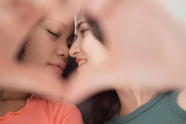 Young African American woman kissing her friend on the lips. clipart