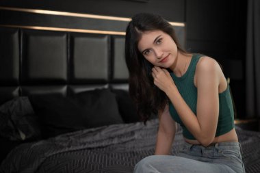 Genç bayan gece vakti odada yatakta oturuyor..