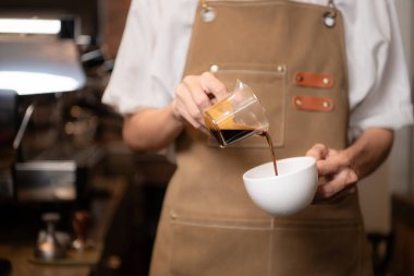 Barista kahve dükkanındaki fincana kahve dolduruyor, yakın plan.